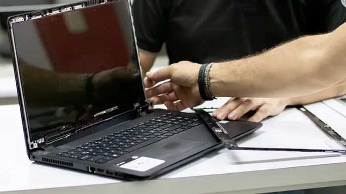 Técnico reparando la pantalla y bisagras de un portátil